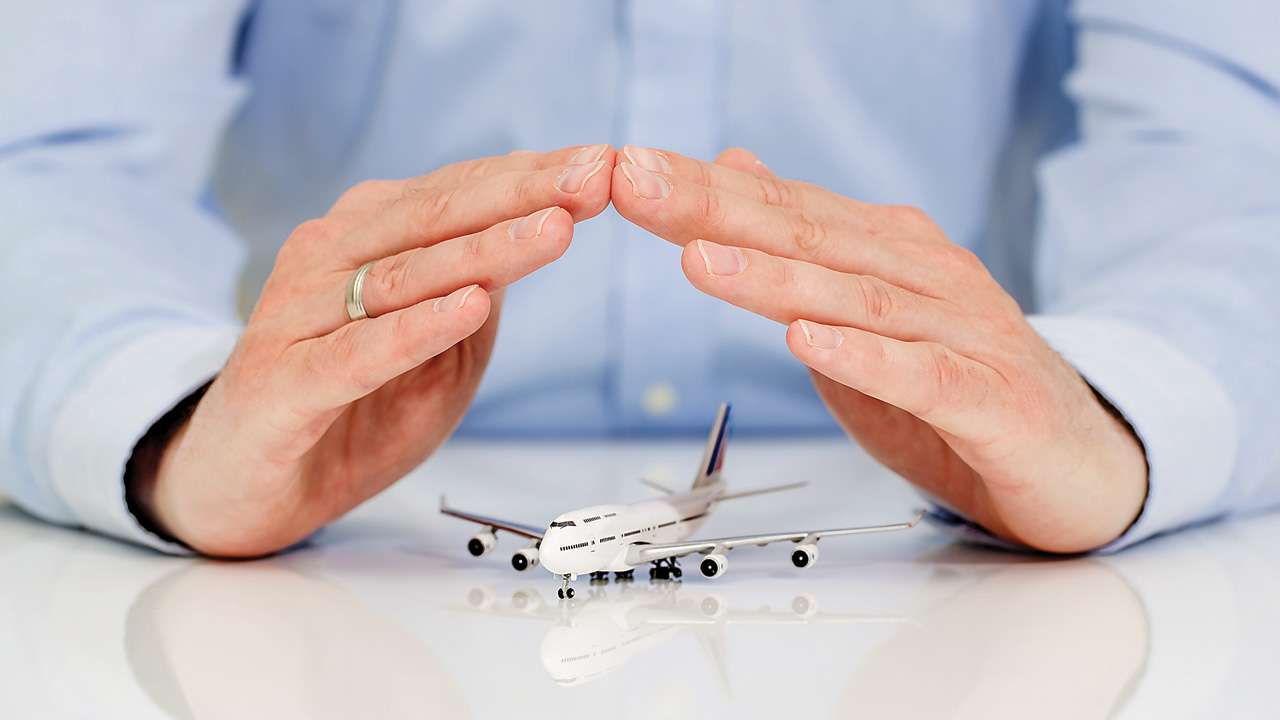 Hands protecting a model airplane – travel insurance coverage Canada