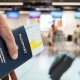 Traveler holding passport at airport – Super Visa insurance Canada